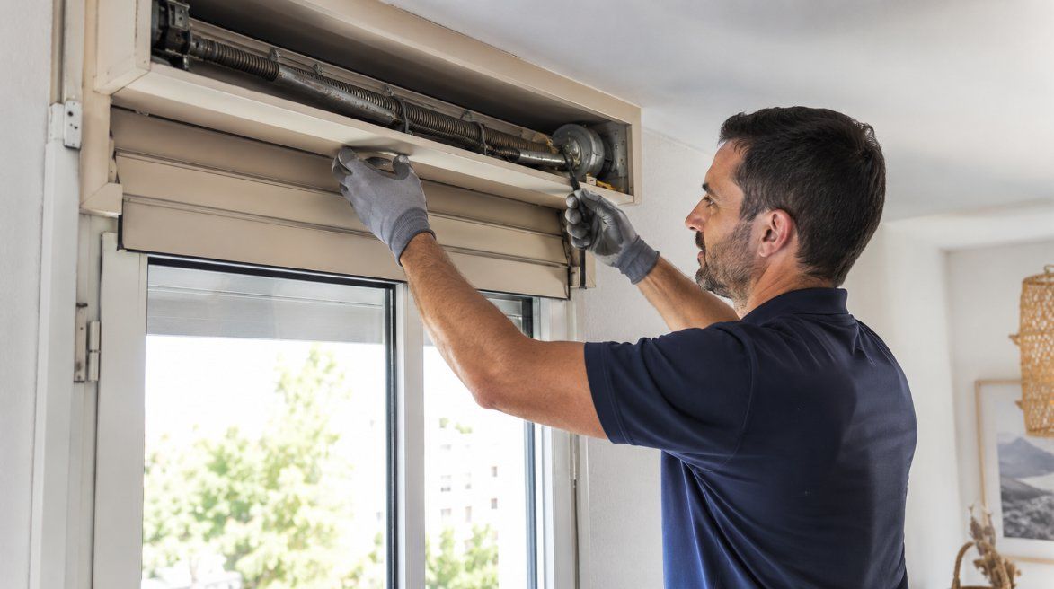 Técnico de Repapercam reparando el cajón de una persiana junto a la ventana